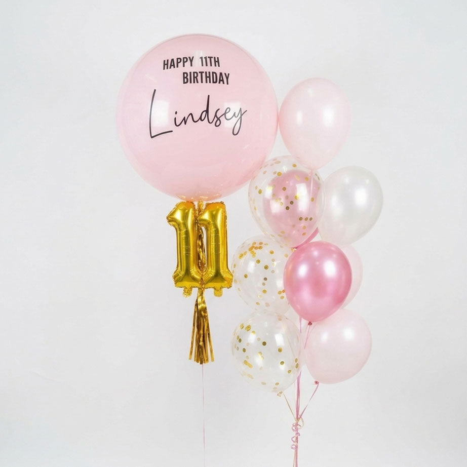 Balloon bouquet with pink balloons and a gold number 11 balloon on a white background