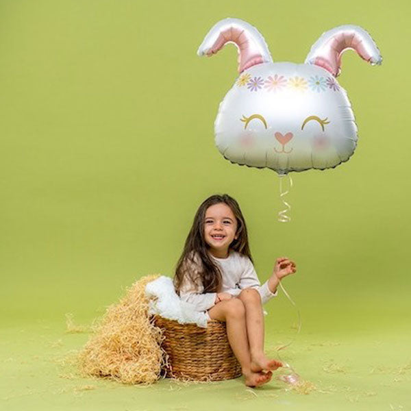 Girl smiling, while holding a Easter bunny balloon