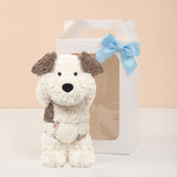 Stuffed dog toy with a blue bow in front of a white gift box on a beige background