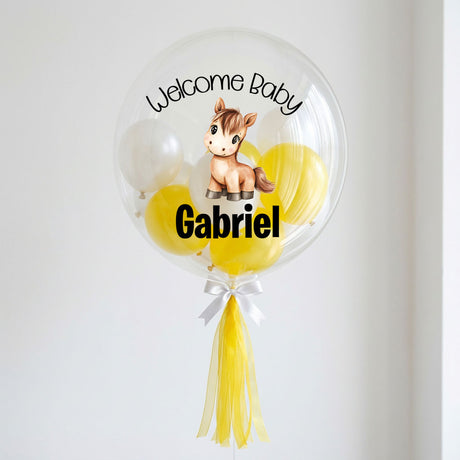 Transparent balloon with a horse illustration, 'Welcome Baby' text, and yellow tassels on a white background.