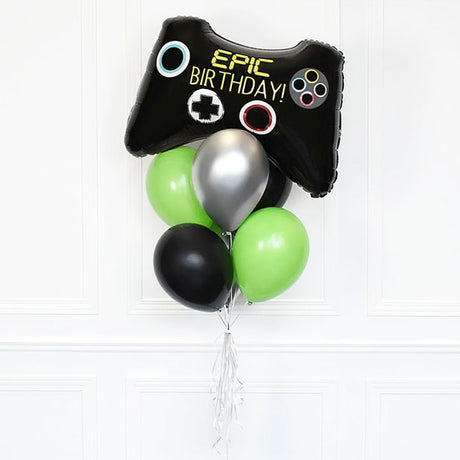 Balloon bouquet with a black game controller-shaped balloon and green, silver, and black balloons on a white background.