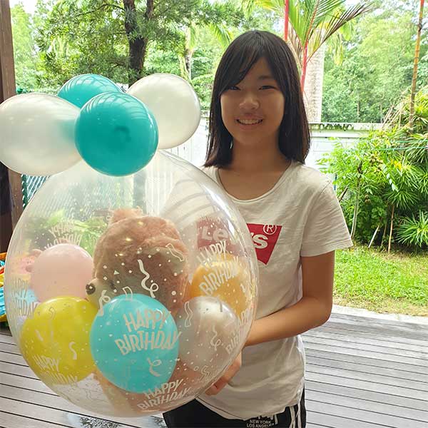 Girl receiving her birthday gift wrapped in a balloon...