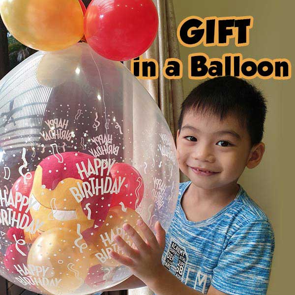 Load image into Gallery viewer, Boy holding up his gift in a balloon set, looking delighted and filled with joy.
