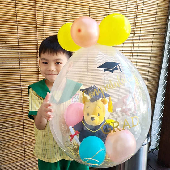 Boy so happy with his new favourite Pooh Bear plush toy impressively wrapped in a Graduation Balloon!