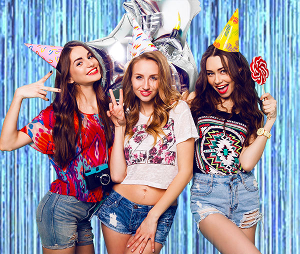 Girls posing in front of the blue foil streamer backdrop.
