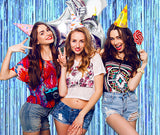 Girls posing in front of the blue foil streamer backdrop.